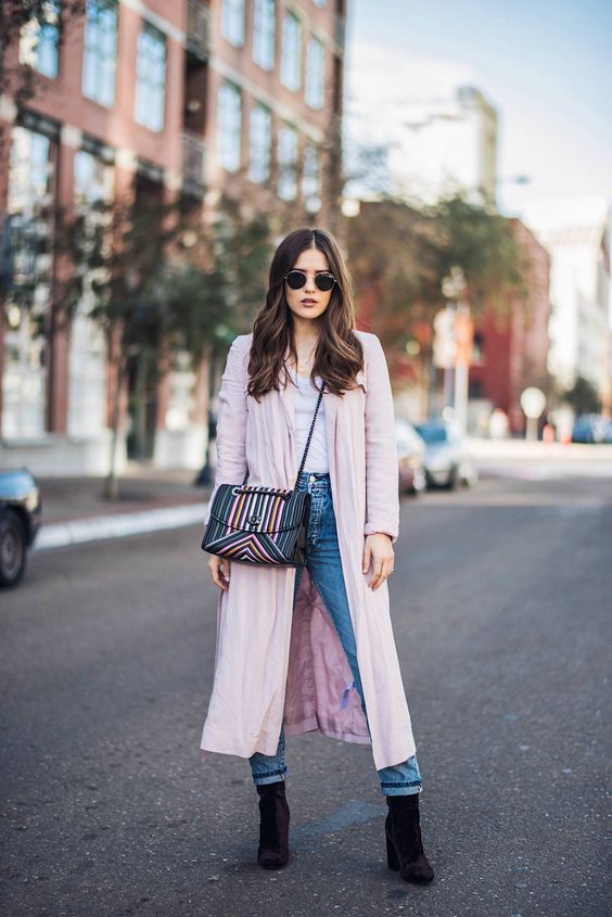 a white tee, blue straight leg jeans, black sock boots, a pink trench and a bright striped bag