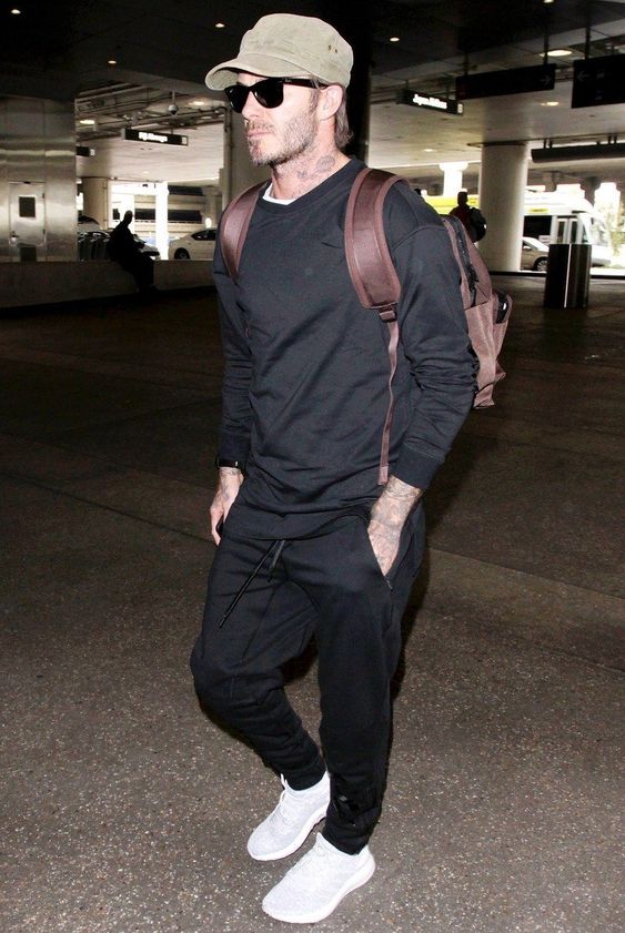 black pants, a black sweatshirt, a white tee, white trainers and a brown backpack
