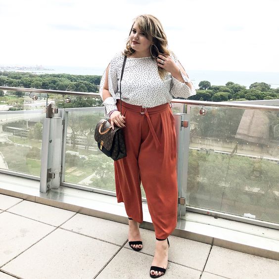 rust-colored culottes, a polka dot blouse, black shoes and a brown bag