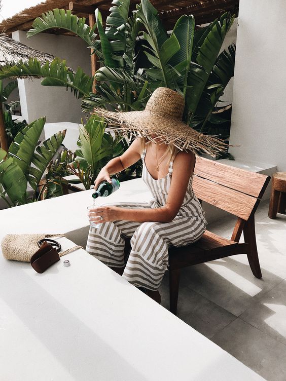 a fringe brim straw ha and a striped linen jumpsuit are all you need for an effortlessly chic look