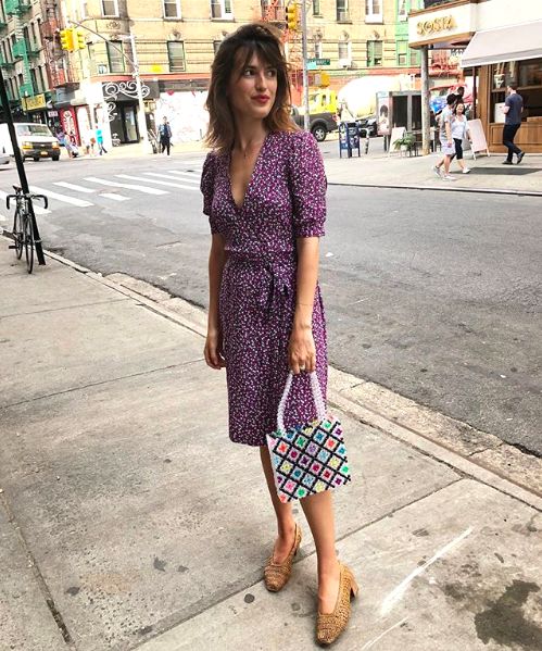 a printed purple wrap over the knee dress, a colorful bag and brown shoes with square toes
