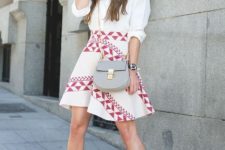 With white button down shirt, printed skirt and gray bag
