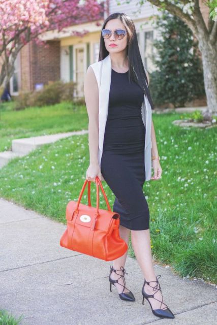 With white long vest, red bag and black high heels