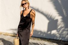a black silk slip dress with side slits, a straw bag and deep red pointed toe slipper mules