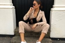 a nude boiler suit with cropped pants, buttons, white sneakers and a small black crossbody