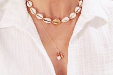 a shell necklace with a gold shell in the center paired with an exquisite pearl one