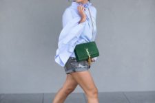 an oversized blue button down, decomposed denim shorts, black slipper mules and a green bag