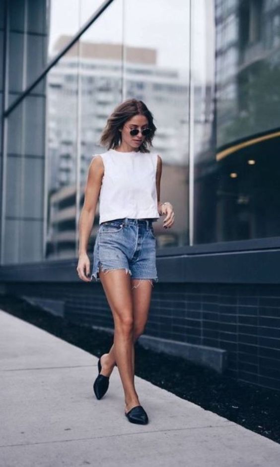 blue distressed denim shorts, a white sleeveless crop top and black slipper mules will keep you cool in every sense on a hot summer day