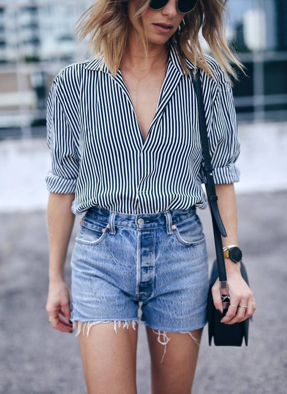 a black and white striped shirt, denim shorts, a black bag make up a chic and stylish look