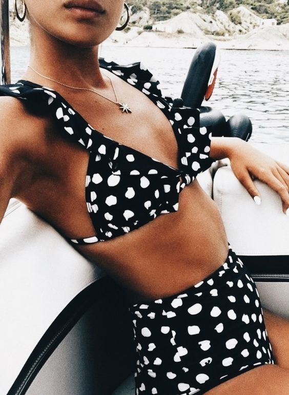 a timeless black and white polka dot bikini with a high waisted bottom and a ruffle top is a chic idea