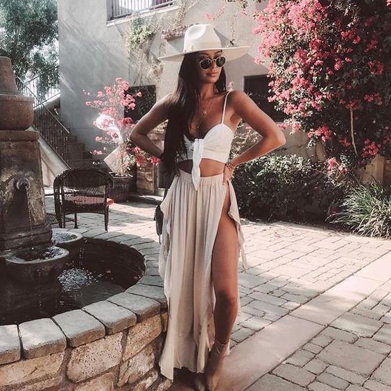 a white bikini with a tied top, a blush maxi skirt with a slit, a white hat