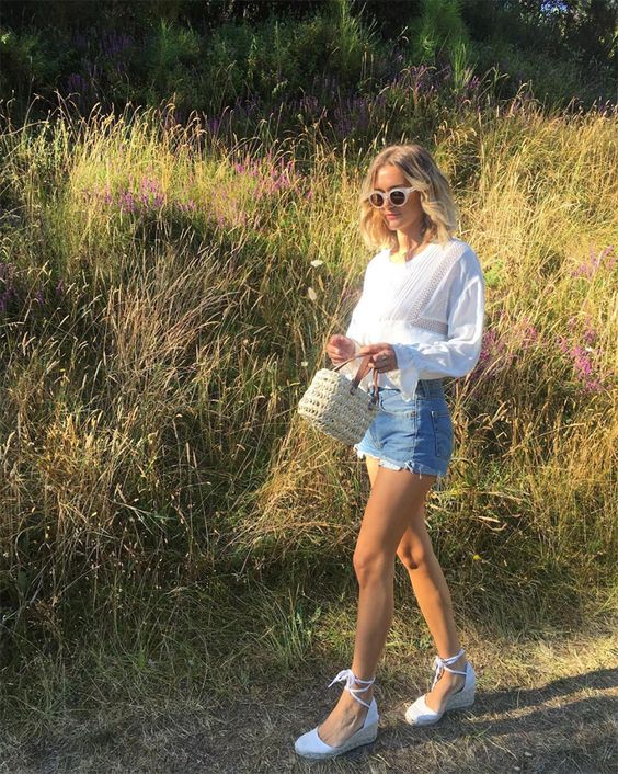 a white blouse, denim shorts with a stepped hem, white espadrilles and a small straw bag