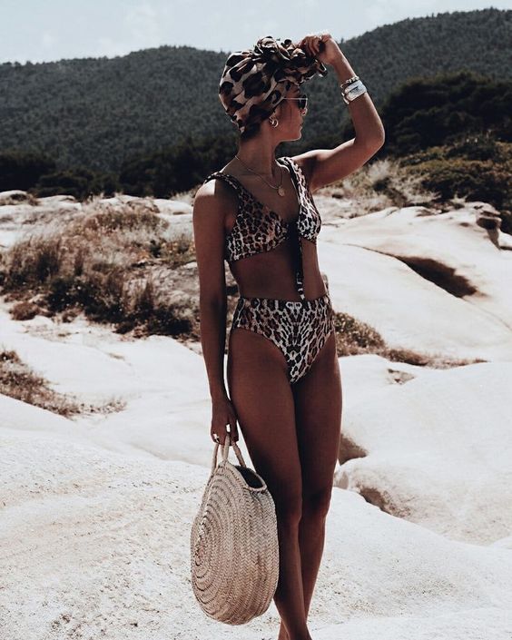 a vintage inspired beach look with a leopard bikini, a top on ties and a high waisted bottom plus s round straw bag