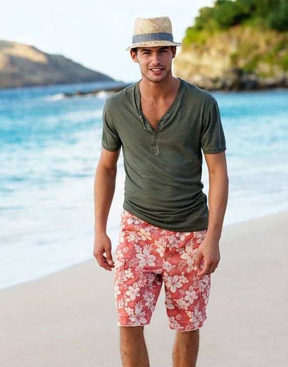 a bright tropical beach look with a green tee, red floral swim trunks and a straw hat is a great option