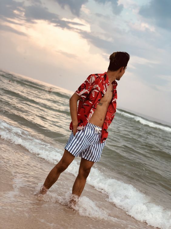 a red tropical print shirt and classic striped trunks make up a colorful and bright beach look