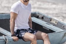 a simple monochromatic beach look with a white tee, dark floral swim trunks and white sneakers
