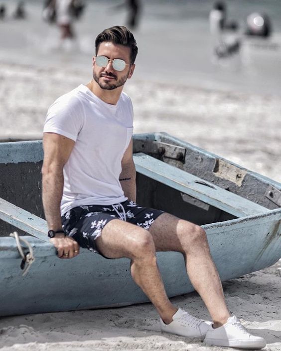 a simple monochromatic beach look with a white tee, dark floral swim trunks and white sneakers