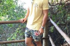 a simple tropical look with a yellow t-shirt, bright florla swim trunks and flipflops is beach-ready