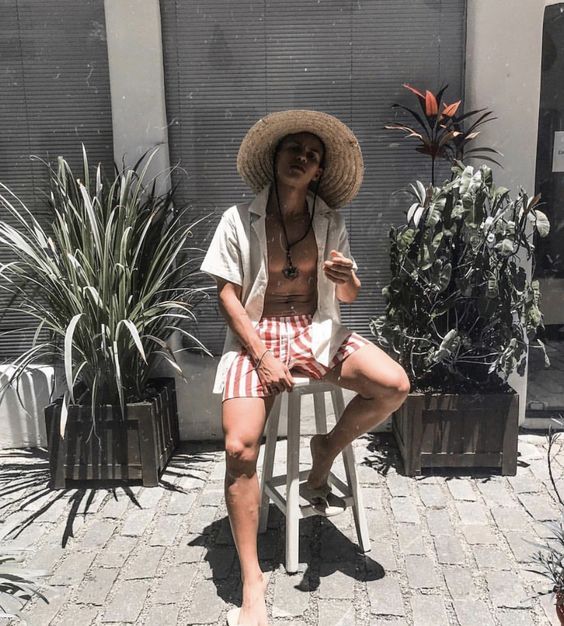 grey shirt, red and white vertical stripe swim shorts, a straw hat for an ultimate holiday look