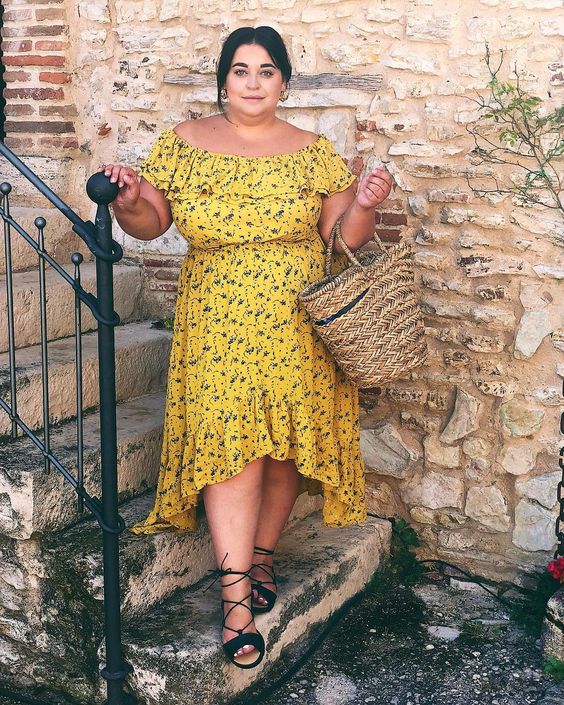 a mustard off the shoulder floral midi dress with a high low skirt, black lace up shoes and a wicker bag