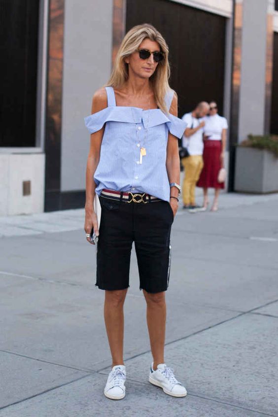 a blue cold shoulder shirt, black denim long shorts, white sneakers for a sporty and fashionable outfit