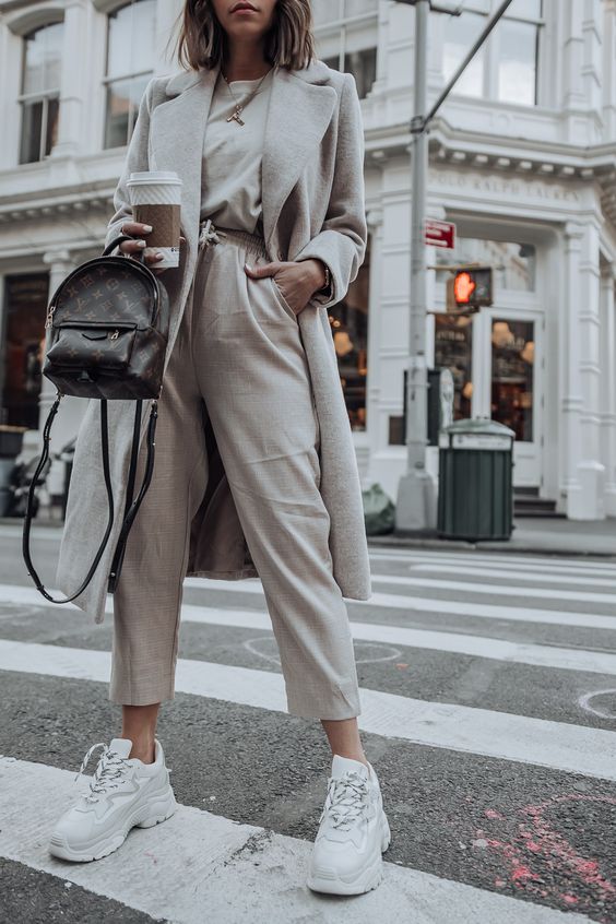 a fashion-forward look with cropped pants, a tee, a neutral coat and large trainers