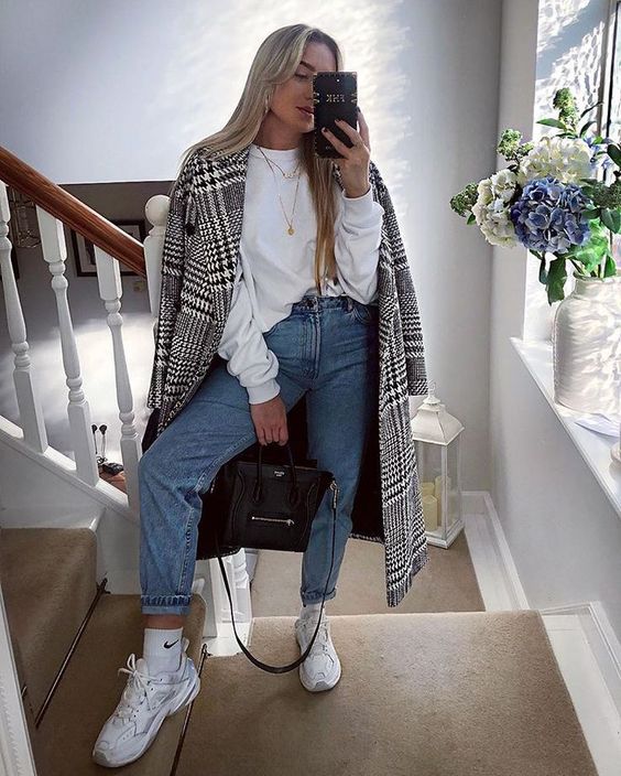 blue high waisted and cropped jeans, white trainers, a white hoodie and a printed coat