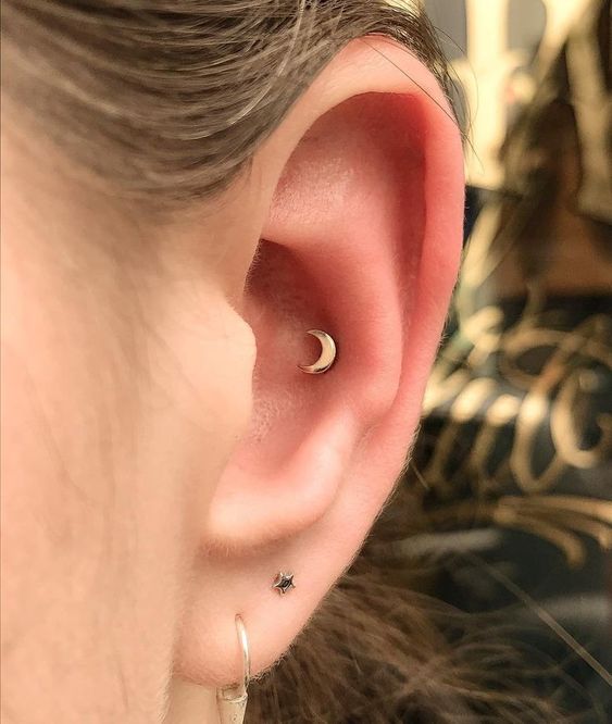 a tiny cute half moon conch piercing in the upper part of the ear cartilage looks very pretty and cute