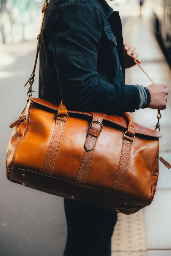 an amber leather bag with multiple belts and a long handle to carry it crossbody