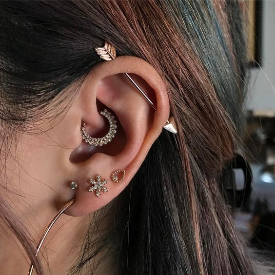 multiple shiny and embellished piercings and an arrow industrial to add a boho feel