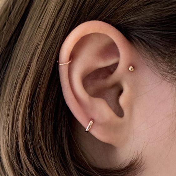 a double helix piercing with two hoops and a gold stud for a bold and modern feel