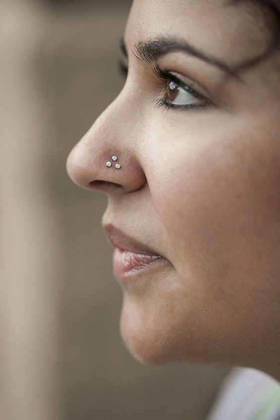 a triple nose stud piercing is a bold and unique idea for a daring girl