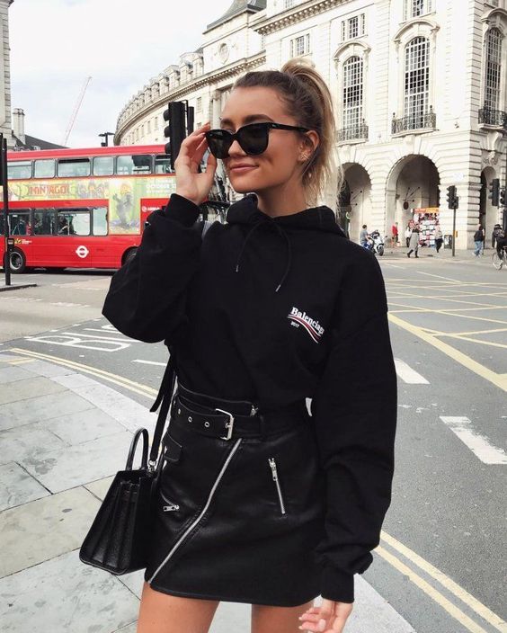 an oversized black hoodie, a black mini skirt with a belt and a black bag for a bold and edgy look