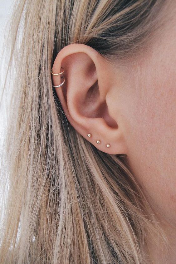 a minimalist look with hoops in the helix and mini studs in the lower part of the ear