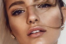 16 shiny eyeshadows, a nose hoop piercing and shiny earrings for a bright party look
