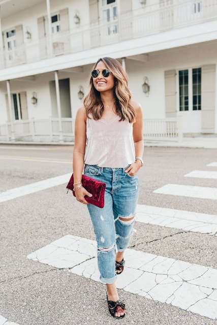 With distressed jeans, velvet clutch and top