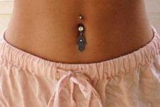 a boho belly button piercing with a hanging hand with rhinestone is a bold idea for a boho girl