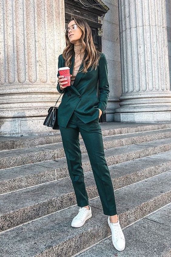 a dark gree pantsuit, a nude turtleneck and white sneakers for a bright fall work look
