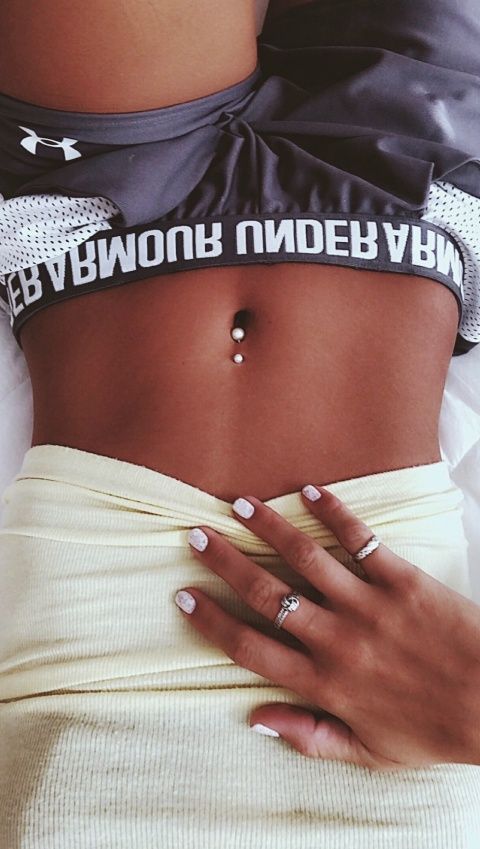 a simple and shiny pearly belly button piercing paired with sporty clothes on