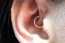 an amber stud, a pearl stud and a gold hoop in the daith make up a bold and creative setup