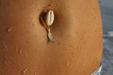 coastal inspired belly button piercing with a seashell and a tiny feather is a cool idea to wear to the beach