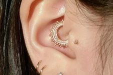 hoops and a triangle stud in the lobe, a stud in the tragus and a bright boho hoop in the daith