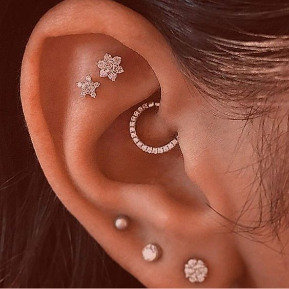shiny ear accessorizing with usual and floral studs and a shiny rhinestone hoop in the daith