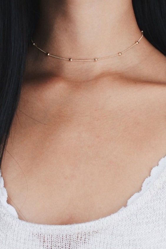 a very delicate gold choker necklace with gold beads is a stylish and minimalist accessory
