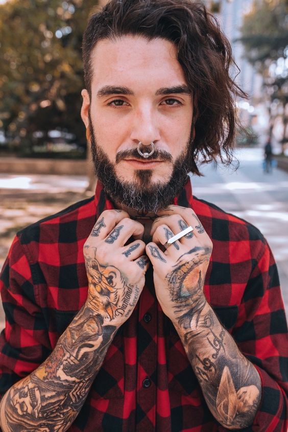 a nose piercing with a large hoop, a beard, moustache and lots of ink for a unique hipster look
