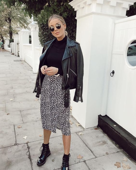 a monochromatic look with a printed knee skirt, black boots, a black turtleneck and a black leather jacket