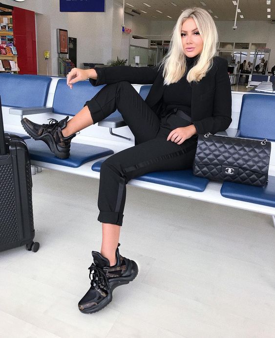 a total black look with a pantsuit, a black turtleneck, trainers, a bag is nice for travelling, too