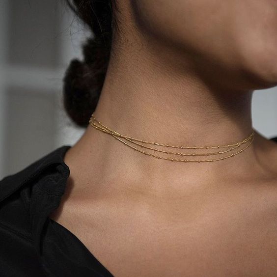 layered gold chain and beads necklaces wrapping aroudn the neck like a choker for a creative touch