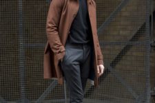 a fall outfit with a black turtleneck, grey joggers, a rust-colored coat and white sneakers