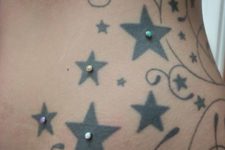 a large star tattoo accented with colorful microdermal piercings is a fun idea